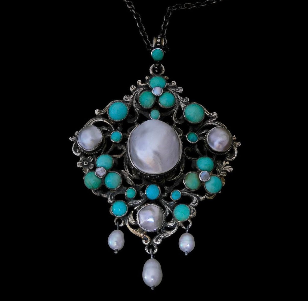 Austro-Hungarian turquoise and pearl silver pendant on dark chain against black background, showing full front detail